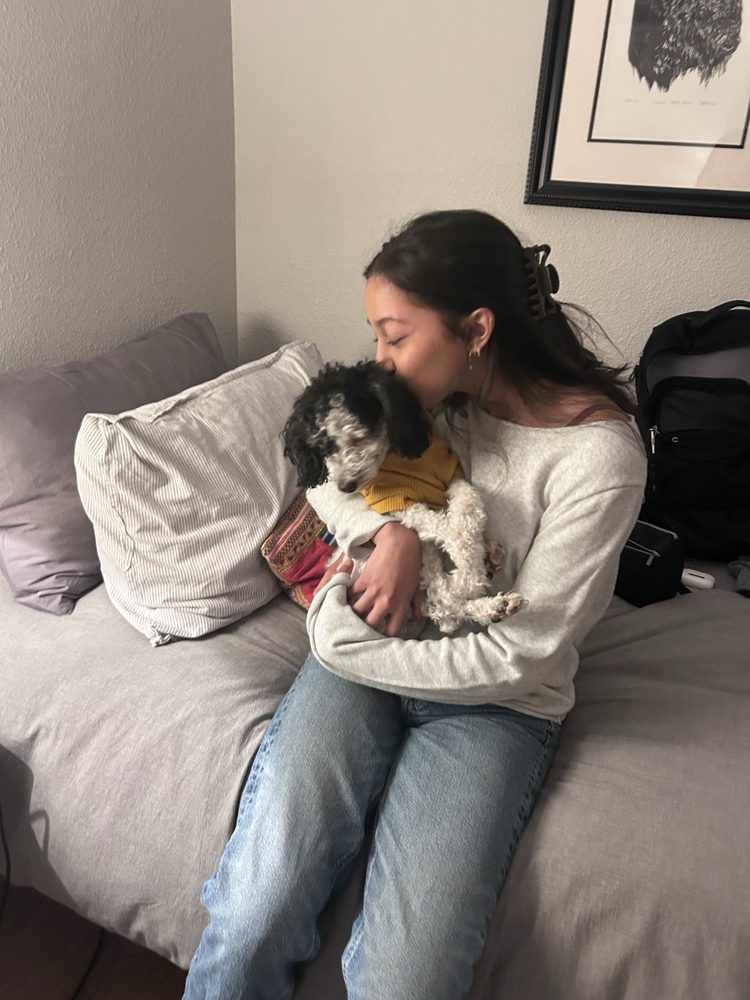 Ashmi kissing a small fluffy dog on the couch